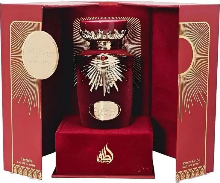 A luxurious red and gold Lattafa SAKEENA bottle by Royal Oud Perfumes sits in a decorative box with radiant sunburst designs, elegant gold accents, Arabic text, and “Eau de Parfum” on the side.