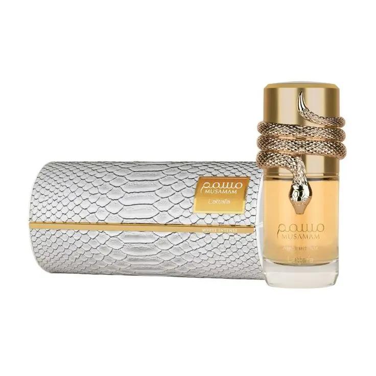 Un frasco de perfume con un diseño de serpiente dorada alrededor de la parte superior se encuentra junto a una caja texturizada con motivos de serpiente plateada y dorada. Ambos llevan la etiqueta Lattafa MUSSAMAM de Royal Oud Perfumes.