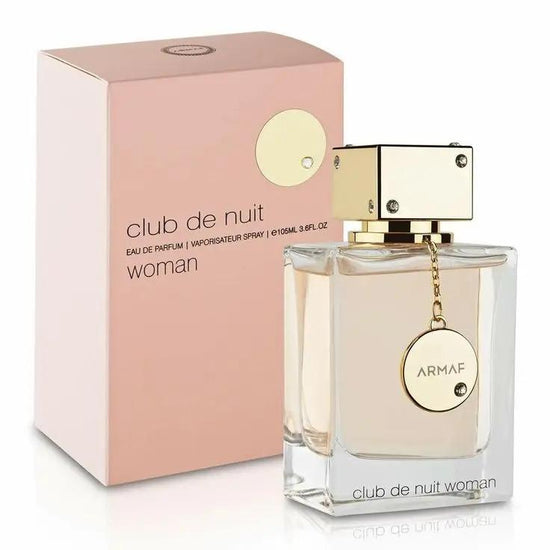 A bottle of Armaf CLUB DE NUIT WOMAN by Royal Oud Perfumes, featuring a gold cap and circular tag, sits before its pink and gold box. This elegant perfume femenino holds a light amber liquid.