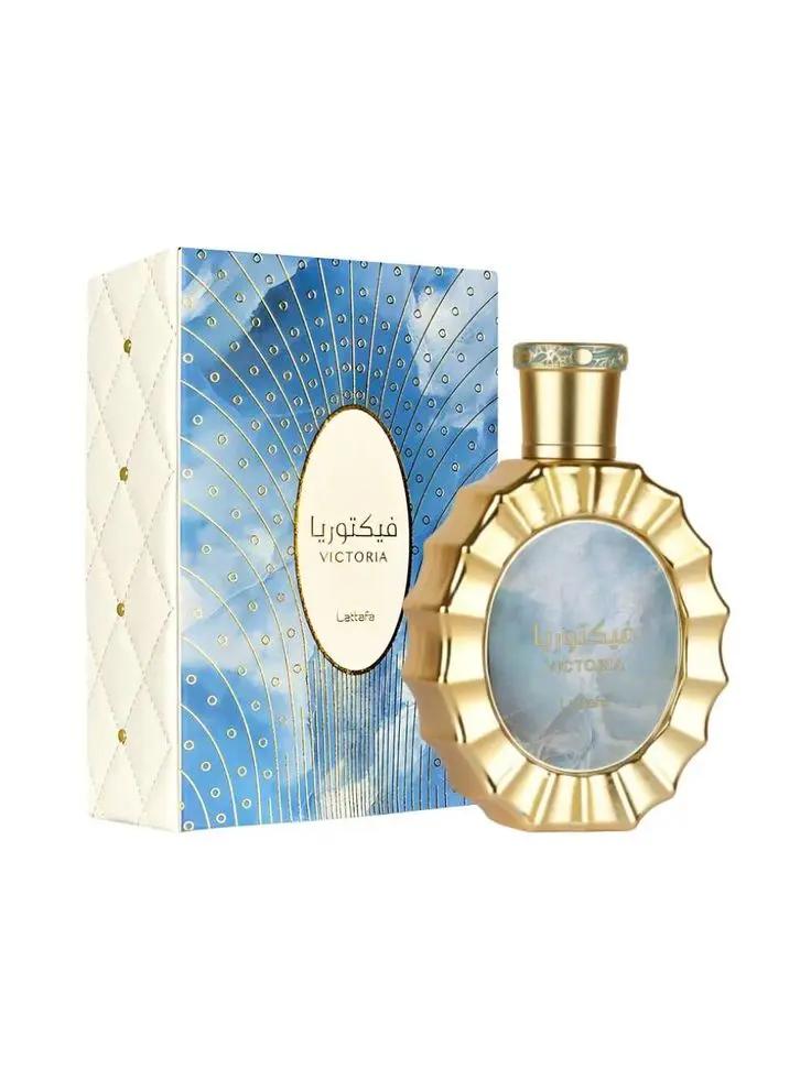 A gold-rimmed Lataffa VICTORIA perfume bottle by Royal Oud Perfumes stands upright on a white surface, with blue and gold peacock feather packaging and Arabic text—an elegant choice for women seeking a refined fragrance.